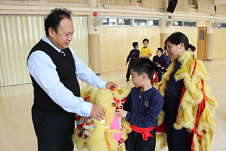 圖右：隊員向朱校長分享舞獅所需要設備服飾