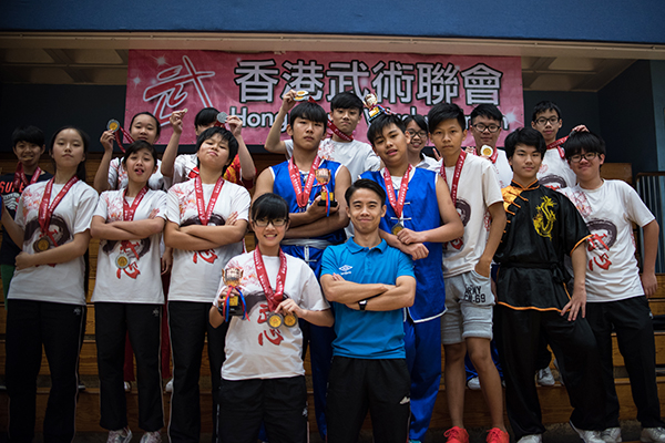 圖上：2015年全港公開賽，石老師(前排藍衫者)與武術隊同學們合照